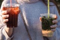 A young girl in a light sweater holds two cocktails in her hands in the rays of sunset Royalty Free Stock Photo