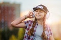 Young girl listening to music on headphones, urban street style, outdoor street style hipster dj woman in black cap and