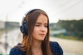 Young girl listening to MP3 player on the street with headphones, smilin