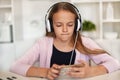 Young girl listening to music on her phone and headset