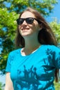 Young girl with long blonde hair in sunglasses and blue shirt walking in the park. Natural beauty people without makeup