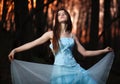 Young girl in a long blue dress dancing in the dark forest Royalty Free Stock Photo