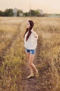 Young girl with long brown hair stay at the meadow.