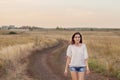 Young girl with long brown hair walking along the road in field Royalty Free Stock Photo