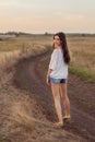 Young girl with long brown hair walking away on the road Royalty Free Stock Photo