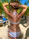 A young girl with long dark hair on a tropical white sand beach with a coconut palm leaf shadow on her back spine. Holiday beach Royalty Free Stock Photo