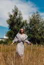 A young girl in a long dress walks in the field