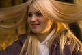 A young girl, with long, flying in the wind, blonde hair, on a walk in the autumn Park. Warm colour. Royalty Free Stock Photo