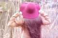 Young girl with long hair in a coat and a hat stands with her back near tree, spring blooming, concept seasonal, infusion, spring