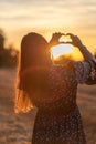 Young girl with long hair holding hands in the form of a heart against the backdrop of sunset, Poland Royalty Free Stock Photo