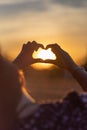 Young girl with long hair holding hands in the form of a heart against the backdrop of sunset, Poland Royalty Free Stock Photo