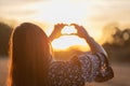 Young girl with long hair holding hands in the form of a heart against the backdrop of sunset, Poland Royalty Free Stock Photo