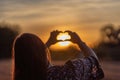 Young girl with long hair holding hands in the form of a heart against the backdrop of sunset, Poland Royalty Free Stock Photo