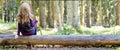 Young girl with long hair sitting on a tree log in autumn forest Royalty Free Stock Photo