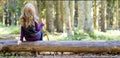 Young girl with long hair sitting on a tree log in autumn forest Royalty Free Stock Photo