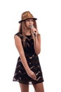 Young girl with long hair wearing a black dress and gold hat with a microphone on a white background Royalty Free Stock Photo
