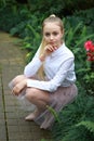 Young girl with long white hair in a white formal shirt and a short light skirt walks in the garden Royalty Free Stock Photo