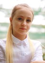 Young girl with long white hair in a white formal shirt and a short light skirt walks in the garden Royalty Free Stock Photo