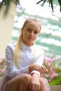 Young girl with long white hair in a white formal shirt and a short light skirt walks in the garden Royalty Free Stock Photo