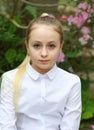 Young girl with long white hair in a white formal shirt and a short light skirt walks in the garden Royalty Free Stock Photo