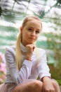 Young girl with long white hair in a white formal shirt and a short light skirt walks in the garden Royalty Free Stock Photo