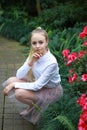 Young girl with long white hair in a white formal shirt and a short light skirt walks in the garden Royalty Free Stock Photo