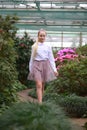 Young girl with long white hair in a white formal shirt and a short light skirt walks in the garden Royalty Free Stock Photo