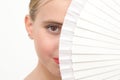 Young girl looking at the camera with her face half covered with a white fan Royalty Free Stock Photo