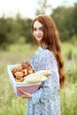 A young girl looking at the camera and holds a basket with homemade cakes on nature. Bakery and bread. Food advertising