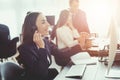 A young girl is looking at a computer screen in the office and is talking on the phone. Royalty Free Stock Photo