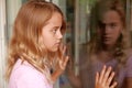 Young girl looking at her reflection in a window