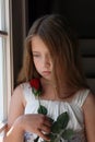 Young girl looking at rose