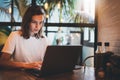 Young girl looking on screen monitor using laptop at cafe workplace, hipster freelancer typing on keyboard laptop indoors Royalty Free Stock Photo