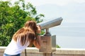Young girl looking thru public binoculars at the seaside