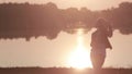 Young girl looks at the beautiful sunrise on the river and drinking coffee from a thermocup