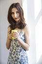 Young girl looks into camera holding a yellow cup of tea