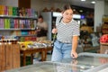 Young girl looks and chooses frozen food in refrigerator in supermarket Royalty Free Stock Photo