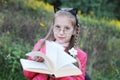 The young girl looks like a teacher - with glasses and a book in her hands. She offers kids more reading books. The concept of Royalty Free Stock Photo