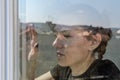 Young girl looks through the window on a sunny day