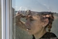 Young girl looks through the window on a sunny day