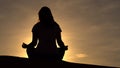 Young girl in a lotus pose meets the dawn in the red desert