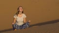 Young girl in a lotus pose meets the dawn in the red desert