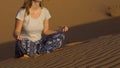 Young girl in a lotus pose meets the dawn in the red desert