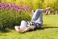 A young girl is lying with bare feet on the green grass near the flowers Royalty Free Stock Photo