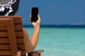 Young girl lying on a beach lounger with mobile phone in hand on