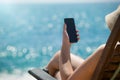 Young girl lying on a beach lounger with mobile phone in hand on Royalty Free Stock Photo