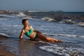 Young girl lying on the beach in the surf of the sea in a swimsuit Royalty Free Stock Photo