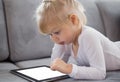 Young girl lying down on couch and playing with tablet computer