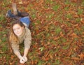 Young girl lying on the fallen yellow leaves in autumn park. Royalty Free Stock Photo