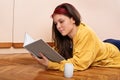 Young girl lying on the floor reading a book Royalty Free Stock Photo